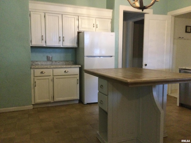 kitchen featuring a chandelier, white cabinets, white fridge, and a kitchen island