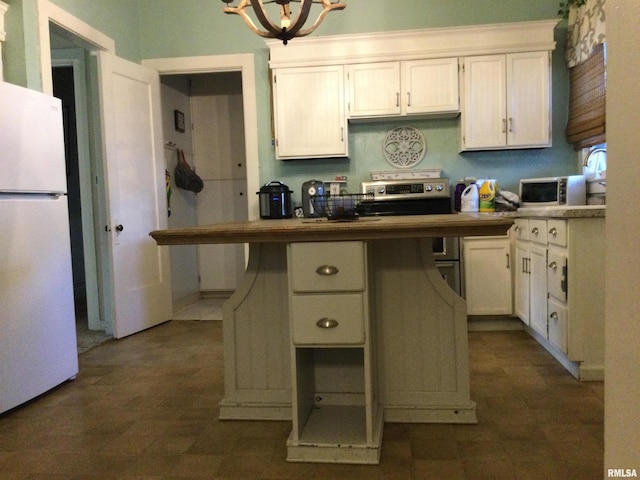 kitchen with stainless steel electric stove, white fridge, white cabinets, and an inviting chandelier