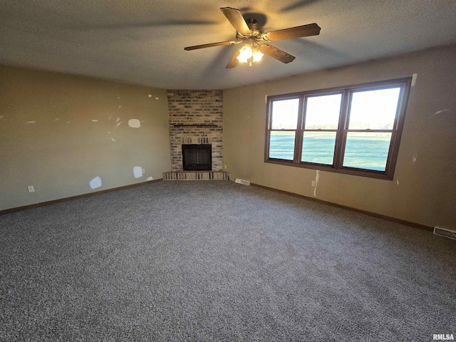 unfurnished living room with baseboards, a water view, a textured ceiling, carpet flooring, and a fireplace