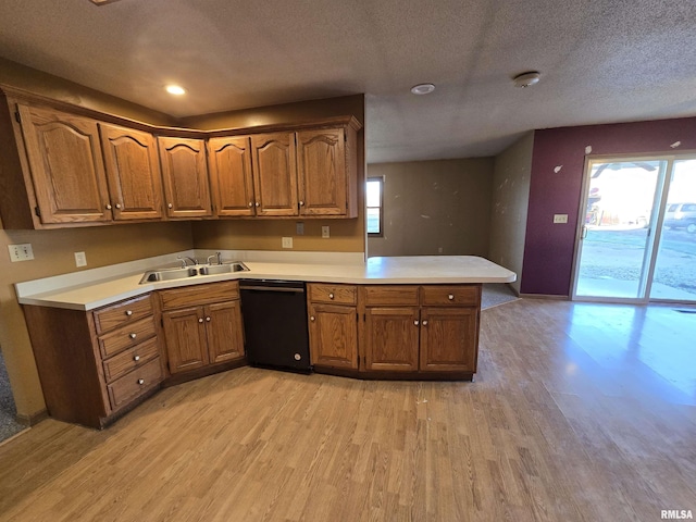 kitchen featuring black dishwasher, light countertops, a sink, and a peninsula