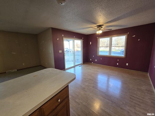 interior space with baseboards, light wood-style flooring, visible vents, and a textured ceiling