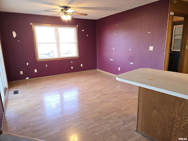 unfurnished room featuring baseboards, light wood-style flooring, visible vents, and a ceiling fan