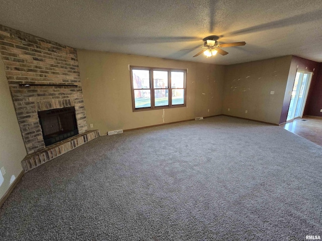 unfurnished living room with a textured ceiling, carpet floors, visible vents, baseboards, and a brick fireplace