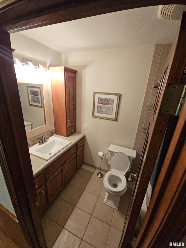 bathroom featuring tile patterned flooring, vanity, and toilet