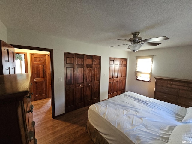 bedroom with ceiling fan, wood-type flooring, a textured ceiling, and multiple closets