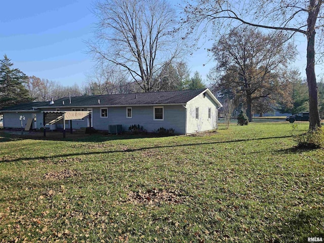 rear view of house featuring cooling unit and a lawn