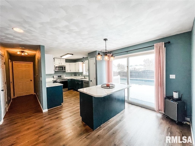 kitchen with appliances with stainless steel finishes, a center island, dark hardwood / wood-style floors, white cabinetry, and hanging light fixtures