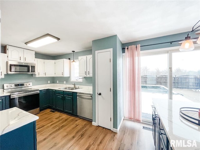 kitchen with sink, white cabinetry, stainless steel appliances, and light wood-type flooring