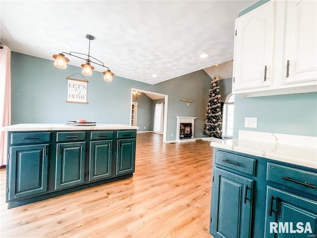 kitchen with white cabinetry, light stone countertops, light wood-type flooring, and hanging light fixtures