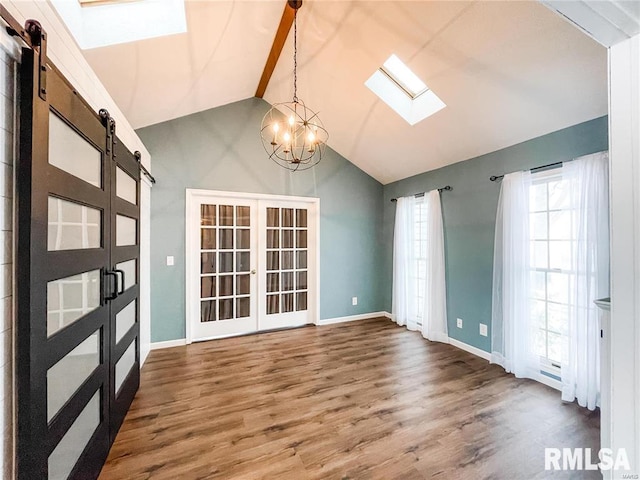 unfurnished dining area with french doors, a skylight, wood-type flooring, a barn door, and a chandelier