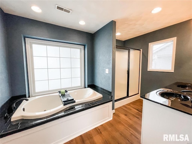 bathroom featuring plus walk in shower, hardwood / wood-style floors, and vanity