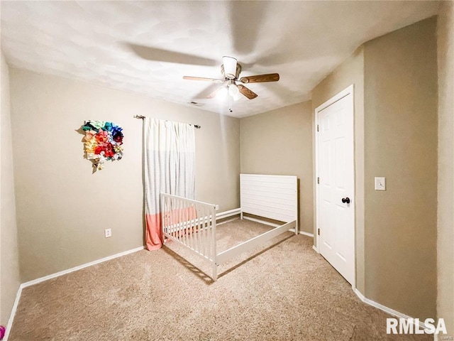 unfurnished bedroom featuring carpet, ceiling fan, and a crib