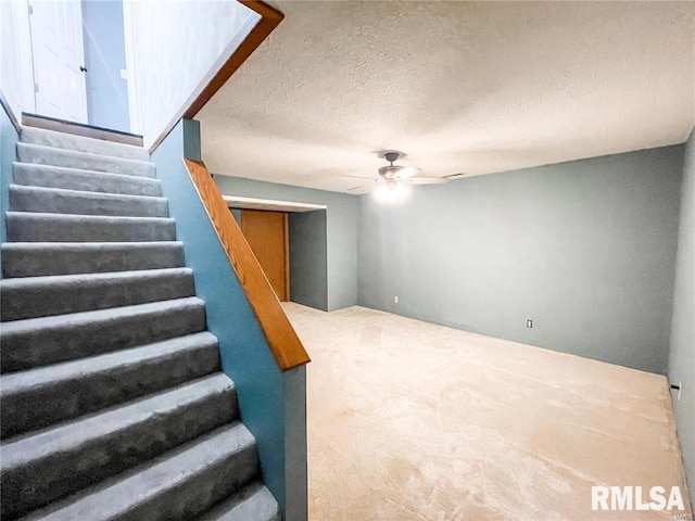 staircase featuring carpet flooring, ceiling fan, and a textured ceiling