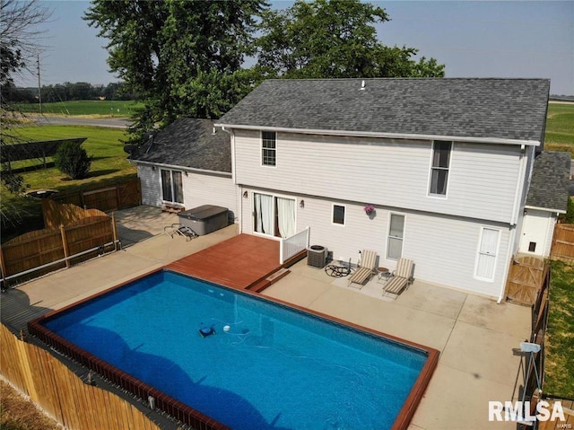 back of property featuring a patio area, central AC unit, and a pool with hot tub