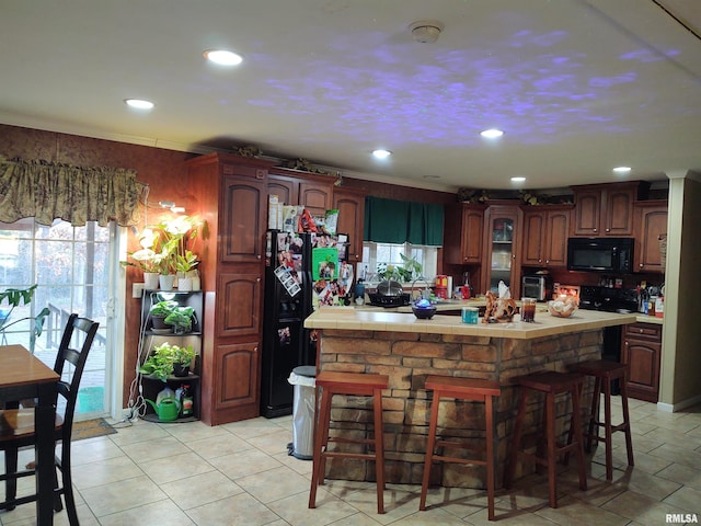 kitchen featuring a center island, a breakfast bar area, and black appliances