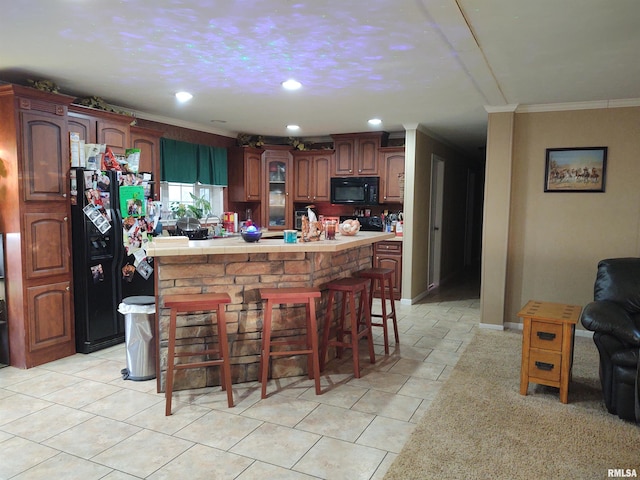 kitchen with a center island, crown molding, a breakfast bar area, light tile patterned flooring, and black appliances