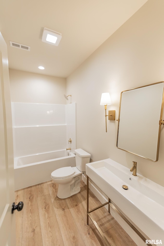 bathroom with hardwood / wood-style floors, bathing tub / shower combination, and toilet