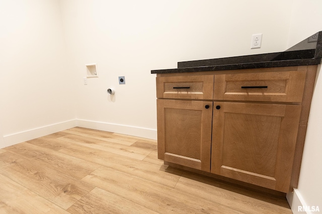 laundry area featuring electric dryer hookup, hookup for a washing machine, cabinets, and light wood-type flooring