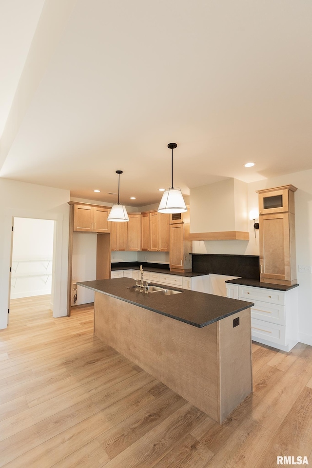 kitchen with pendant lighting, light brown cabinetry, sink, a kitchen island with sink, and light wood-type flooring