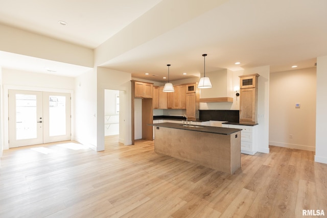 kitchen with a kitchen island, decorative light fixtures, sink, light wood-type flooring, and french doors