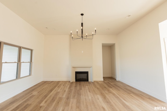 unfurnished living room featuring light wood-type flooring and a notable chandelier