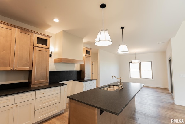 kitchen featuring sink, light hardwood / wood-style floors, a center island with sink, light brown cabinetry, and decorative light fixtures