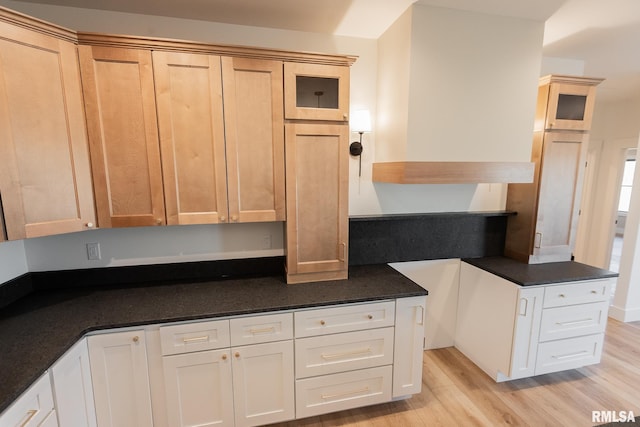 kitchen featuring light brown cabinets, light wood-type flooring, and dark stone counters