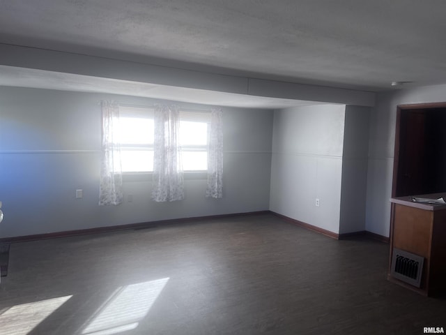 spare room featuring dark wood-type flooring and a textured ceiling