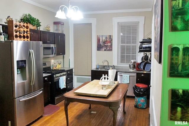 kitchen with sink, light wood-type flooring, ornamental molding, and stainless steel appliances