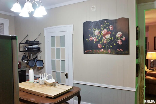 dining area with ornamental molding, wooden walls, and a chandelier