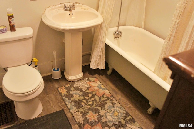 bathroom featuring a washtub, wood-type flooring, and toilet