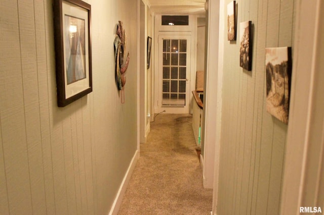 hall with wood walls and light colored carpet