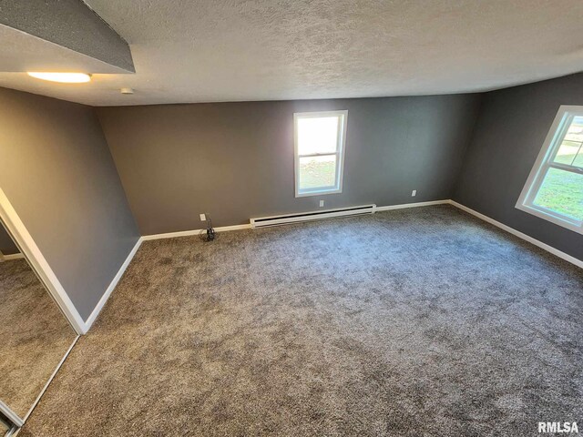 carpeted spare room with a textured ceiling and a baseboard heating unit