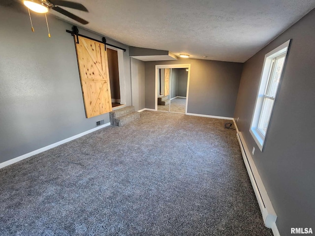 carpeted spare room with a textured ceiling, a barn door, a baseboard radiator, and ceiling fan