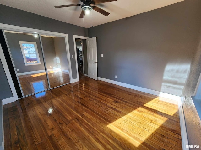 unfurnished bedroom featuring hardwood / wood-style floors, ceiling fan, and a closet