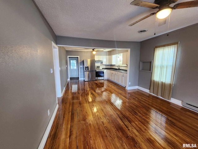 kitchen with a textured ceiling, stainless steel appliances, sink, hardwood / wood-style floors, and white cabinetry