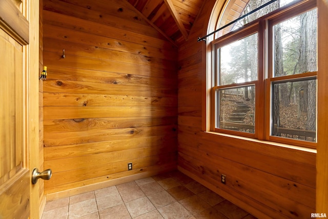 tiled spare room with lofted ceiling and wood walls