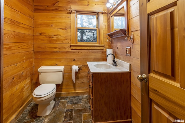 bathroom featuring vanity, wooden walls, and toilet