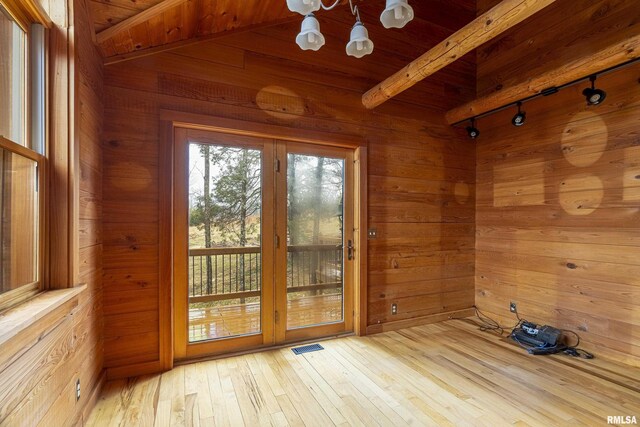 entryway with an inviting chandelier, track lighting, wooden walls, beam ceiling, and light hardwood / wood-style floors