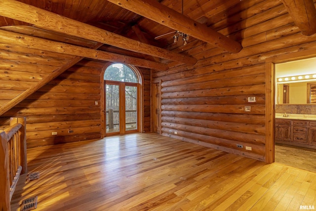 interior space featuring log walls, vaulted ceiling with beams, wooden ceiling, and light hardwood / wood-style flooring