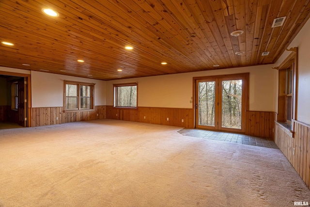 spare room featuring wooden walls, wooden ceiling, and plenty of natural light