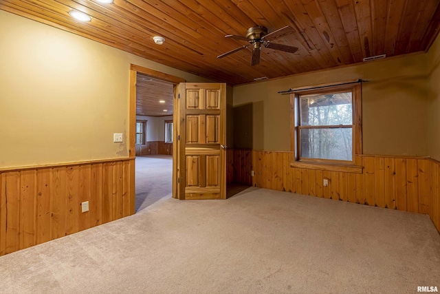 carpeted spare room featuring wood ceiling, ceiling fan, and wood walls