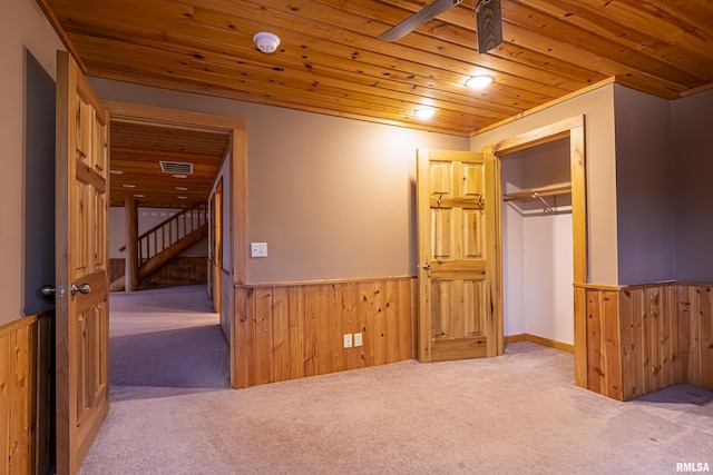 unfurnished bedroom with light carpet, wood ceiling, and wooden walls