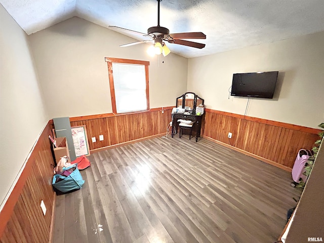 miscellaneous room featuring wooden walls, vaulted ceiling, hardwood / wood-style flooring, ceiling fan, and a textured ceiling