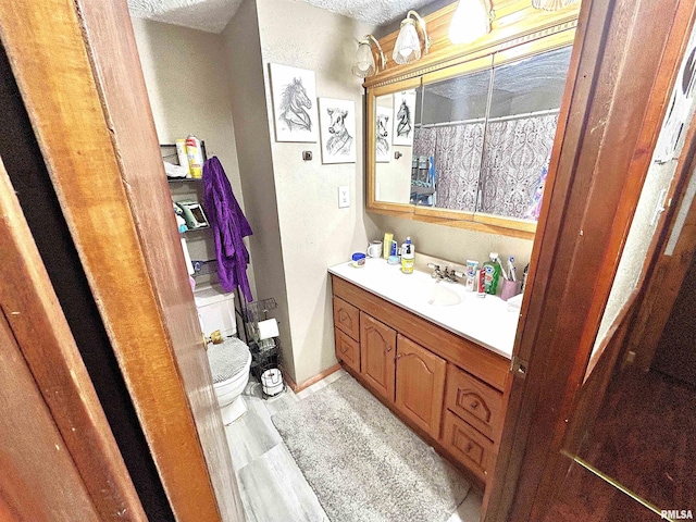 bathroom featuring a textured ceiling, vanity, and toilet