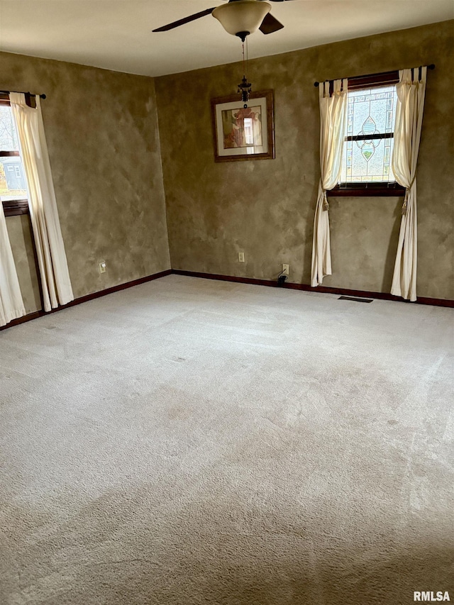 empty room with carpet, plenty of natural light, and ceiling fan