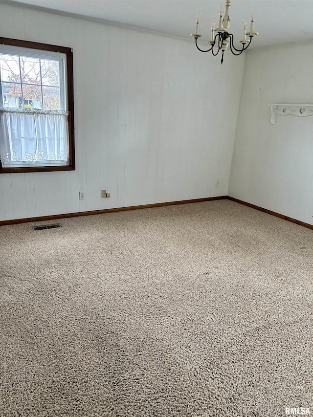 empty room with carpet flooring and a notable chandelier