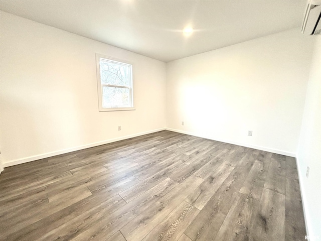 unfurnished room with an AC wall unit and dark hardwood / wood-style flooring