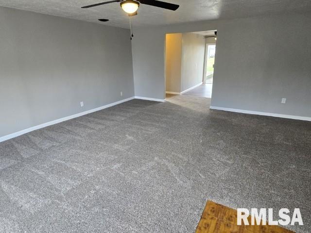 empty room with ceiling fan, dark carpet, and a textured ceiling