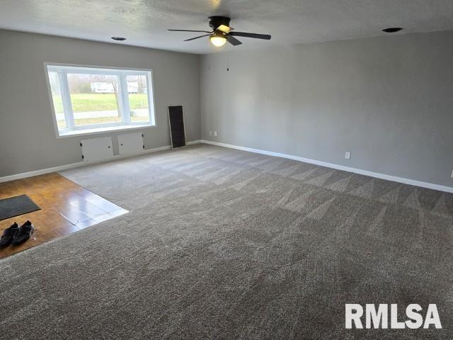 unfurnished living room featuring ceiling fan, carpet, and a textured ceiling